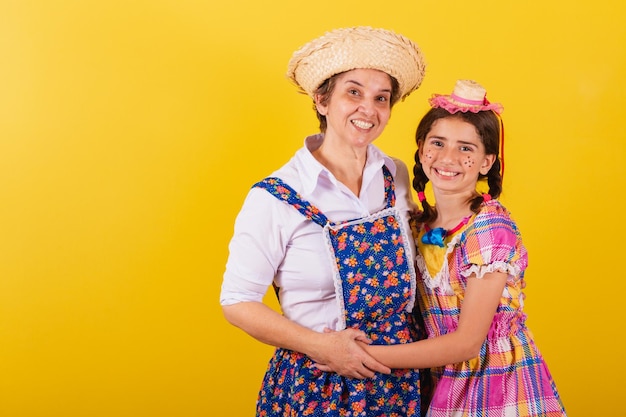 Abuela y nieta vestidas con ropa típica de Festa Junina Abrazándose y sonriendo