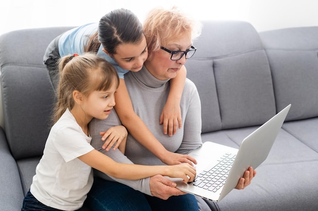 La abuela con nietas usa una computadora.