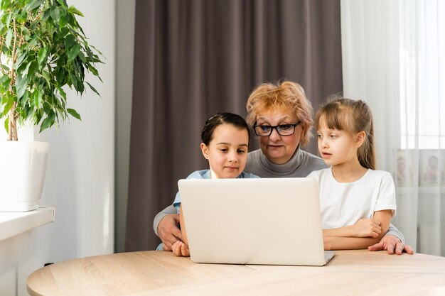 La abuela con nietas usa una computadora.