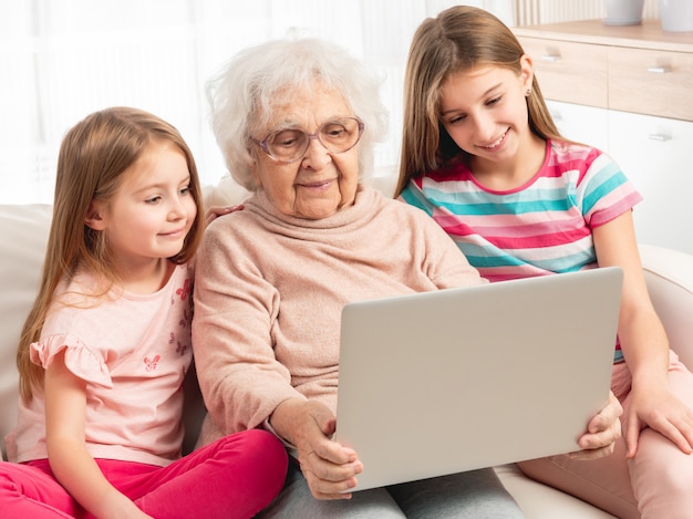 abuela y nietas usando una computadora portátil