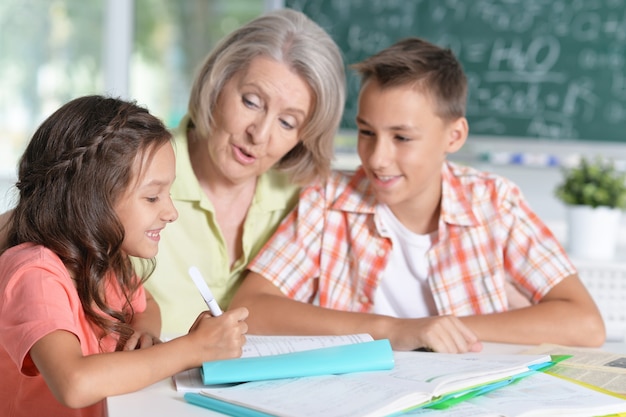 Abuela con nietos haciendo los deberes, juntos en casa