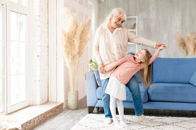 Abuela con niña bailando en casa