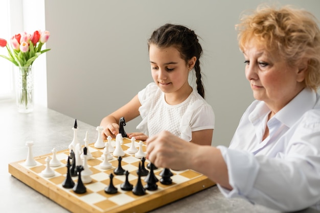 Abuela y niña jugando al ajedrez juntos en casa.