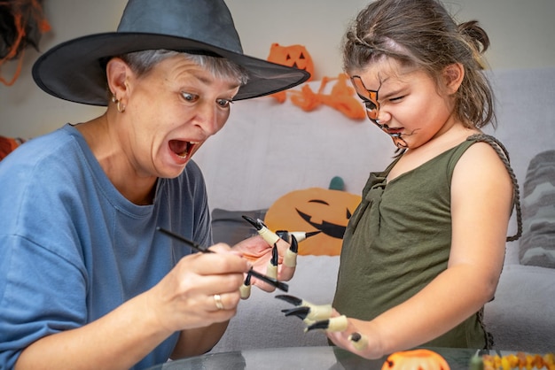 Abuela con niño pinta uñas de disfraces preparándose para Halloween