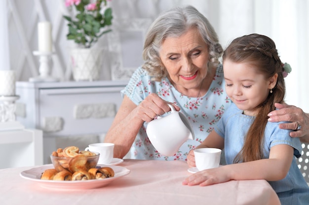 Abuela con una pequeña nieta bebiendo té