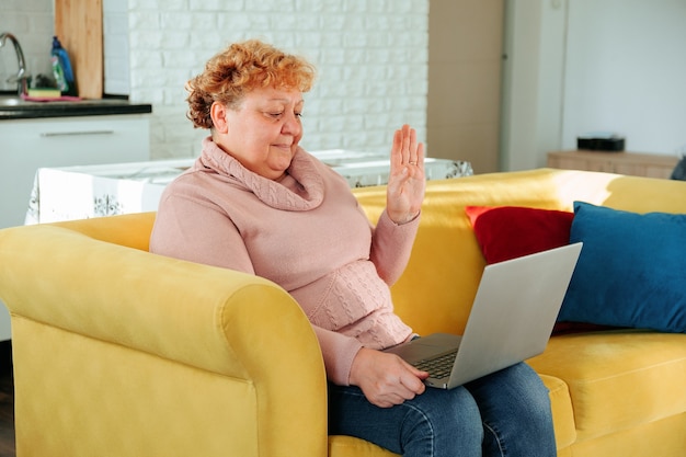 Abuela positiva sonriendo de mediana edad anciana relajante sosteniendo portátil feliz socializado vejez con ...