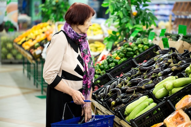 La abuela recoge berenjenas en el supermercado cierra las manos