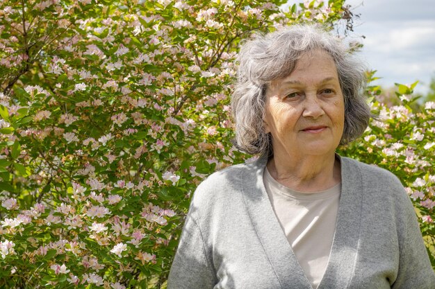 La abuela se sienta en un banco del parque y sonríe