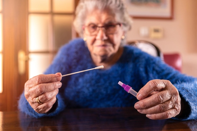 Abuela sosteniendo un hisopo de algodón para la nariz para recoger un posible COVID19 positivo