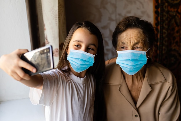 La abuela con su nieto enmascarado juega cerca de la ventana de su casa. Quédate en casa. cuarentena Coronavirus (COVID-19.