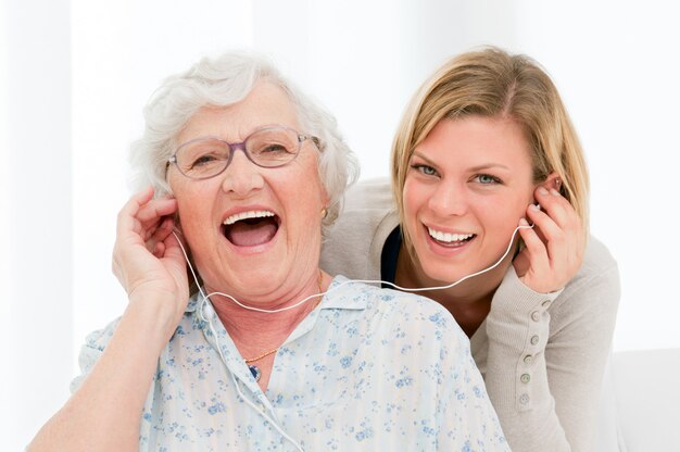 Abuela súper feliz y emocionada escuchando música con su nieta en casa