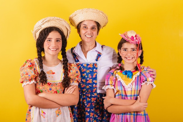 Abuela y sus dos nietas vestidas con ropa típica de Festa Junina Mirando a la cámara sonriendo