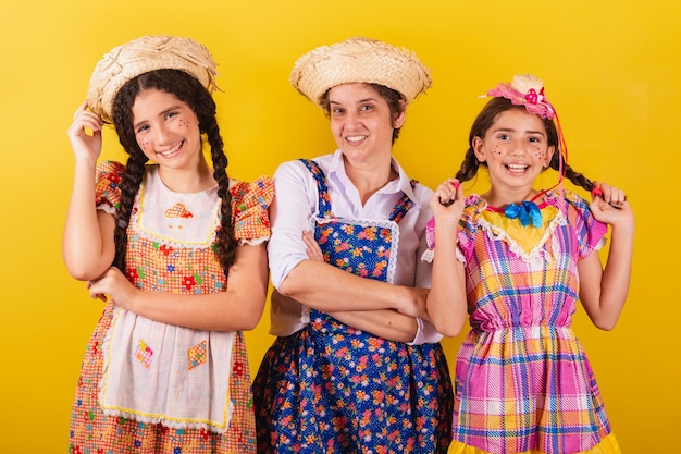 Foto abuela y sus dos nietas vestidas con ropa típica de festa junina posando para una foto juntas