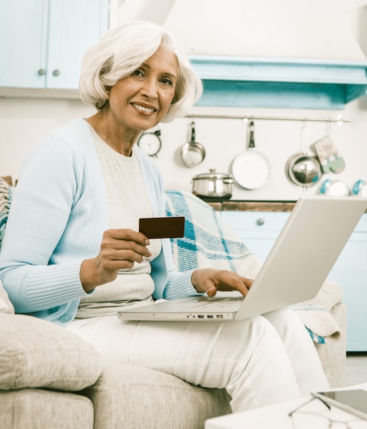La abuela usa una tarjeta de crédito durante las compras en línea