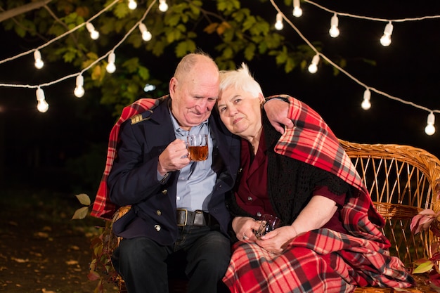 El abuelo y la abuela beben té en el parque.