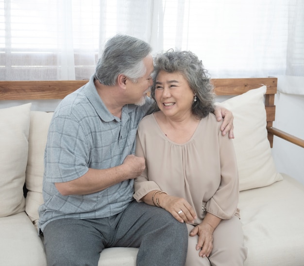 El abuelo y la abuela se sientan en el entrenador en la sala de estar en casa y tienen tiempo libre en los estilos de vida de jubilación.