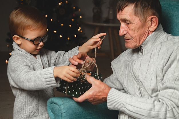 Abuelo anciano y su nieto dan y abren un regalo de Navidad