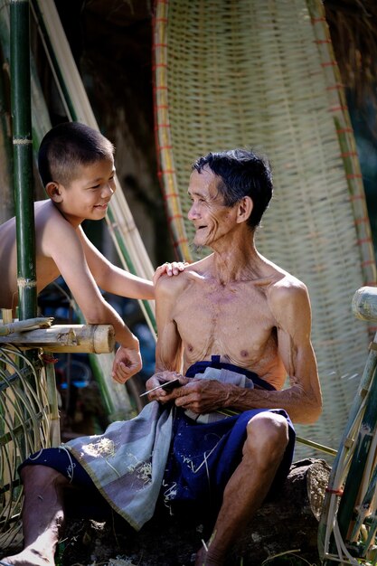 Abuelo sin camisa y nieto sonriendo al aire libre