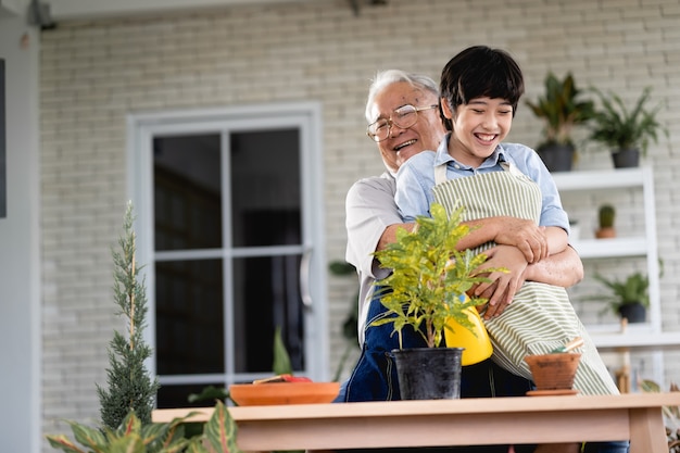 Abuelo cultivando un huerto y enseñando a su nieto cuidar la planta en el interior