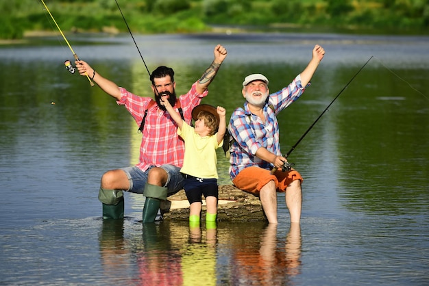 Abuelo emocionado, padre e hijo están pescando con mosca en el río