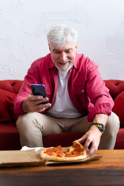 Abuelo empoderado comiendo pizza y relajándose