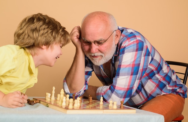 Abuelo enseñando a su nieto a jugar al ajedrez hombre senior pensando en su próximo movimiento en el juego de ajedrez