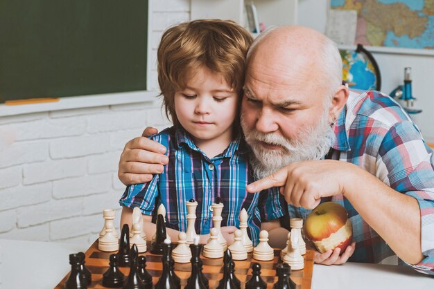 Abuelo de familia de hombres enseñando a nieto a jugar al ajedrez padre y paternidad