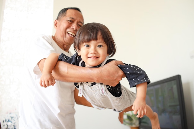 Abuelo feliz llevando a su adorable nieta en casa