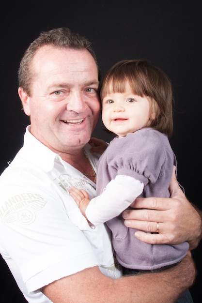 Abuelo feliz sosteniendo a una pequeña nieta en sus brazos