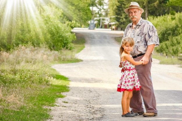 Un abuelo feliz con su nieta en la naturaleza en el parque va por el camino del viaje