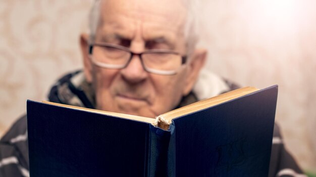 Foto abuelo con gafas lee un libro en la habitación ocio para ancianos