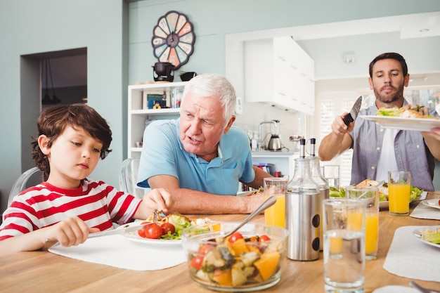 Abuelo hablando con su nieto mientras está sentado en la mesa del comedor