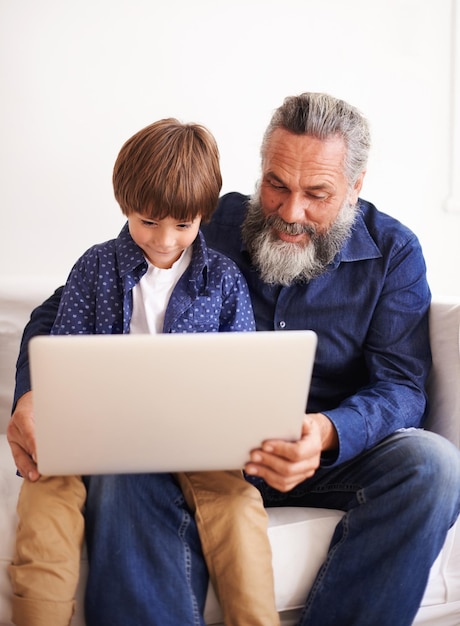Abuelo hijo y computadora portátil en el sofá con amor y unión junto con juegos en línea en la sala de estar feliz niño de la familia y computadora para dibujos animados en el salón relajarse y suscripción a películas en vacaciones