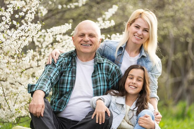 Abuelo de hombre mayor sentado al aire libre en el parque. Los ancianos jubilados se relajan y disfrutan de actividades al aire libre junto con su hija y su nieta. Concepto de relación familiar