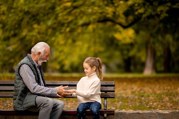 Abuelo jugando juego de bofetadas de manos rojas con su nieta en el parque el día de otoño