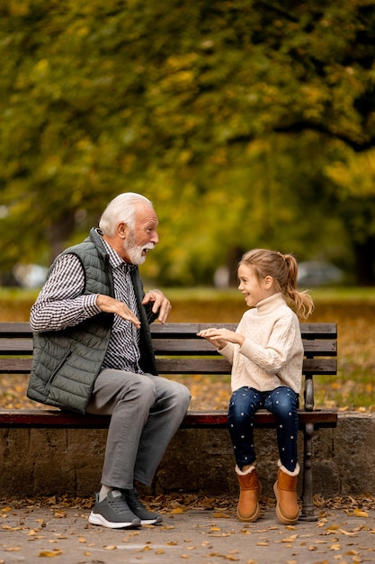 Abuelo jugando juego de bofetadas de manos rojas con su nieta en el parque el día de otoño