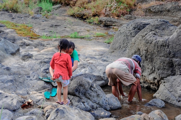 Foto un abuelo jugando con sus dos nietas en el río