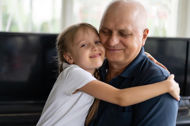 Abuelo mayor con nieta pequeña adentro sentado en la mesa.