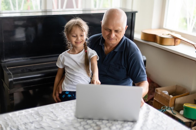 Abuelo mayor con nieta pequeña adentro sentado en la mesa.