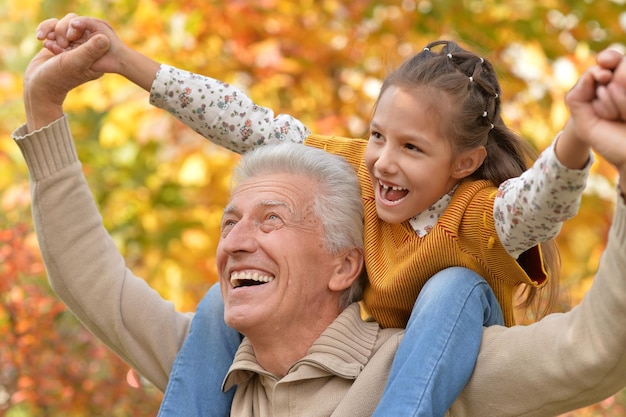 Abuelo y nieta divirtiéndose en el parque otoñal