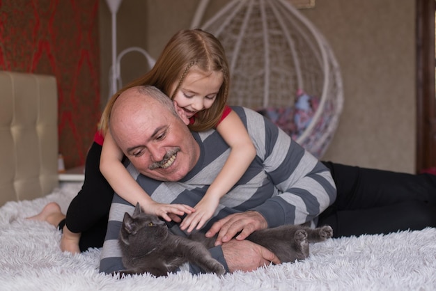 abuelo y nieta juegan juntos con un gato