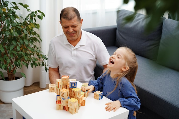 Abuelo y nieta jugando cubos de madera en el salón