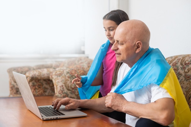 Abuelo y nieta con laptop y bandera de Ucrania