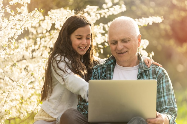 Abuelo y nieta con laptop en el jardín