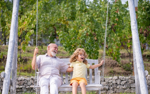 Abuelo y nieto emocionados y asombrados balanceándose en un fin de semana al aire libre con el abuelo