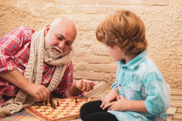 Abuelo y nieto juegan ajedrez y sonríen mientras pasan tiempo juntos en casa Chessman