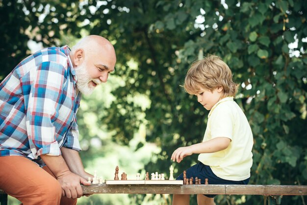 Foto abuelo y nieto jugando al ajedrez abuelo y nieto jugando al ajedrez y sonriendo mientras pasan tiempo juntos en el parque