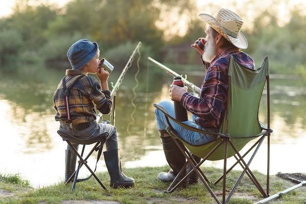 abuelo y nieto pescando y bebiendo té