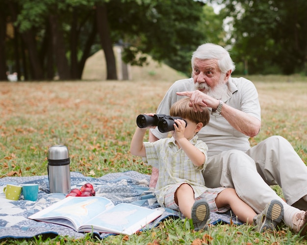 Abuelo y nieto usando binoculares al aire libre