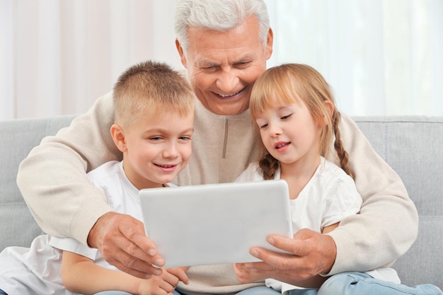 Abuelo con nietos usando tableta en el sofá